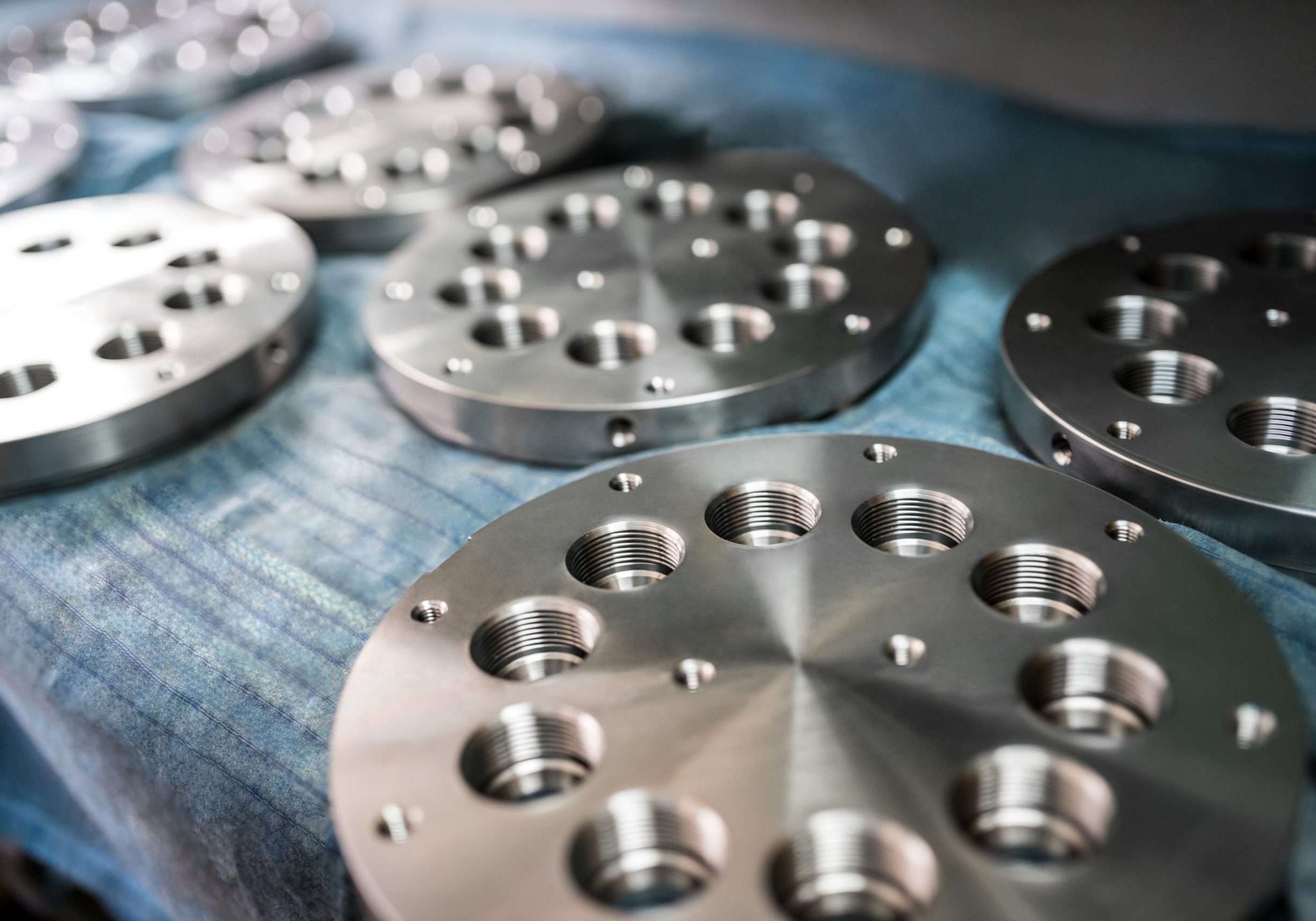 Close-up chrome metal circles with holes lie on shelves awaiting transportation and marketing. Concept manufacturing of metal components for mechanical engineering